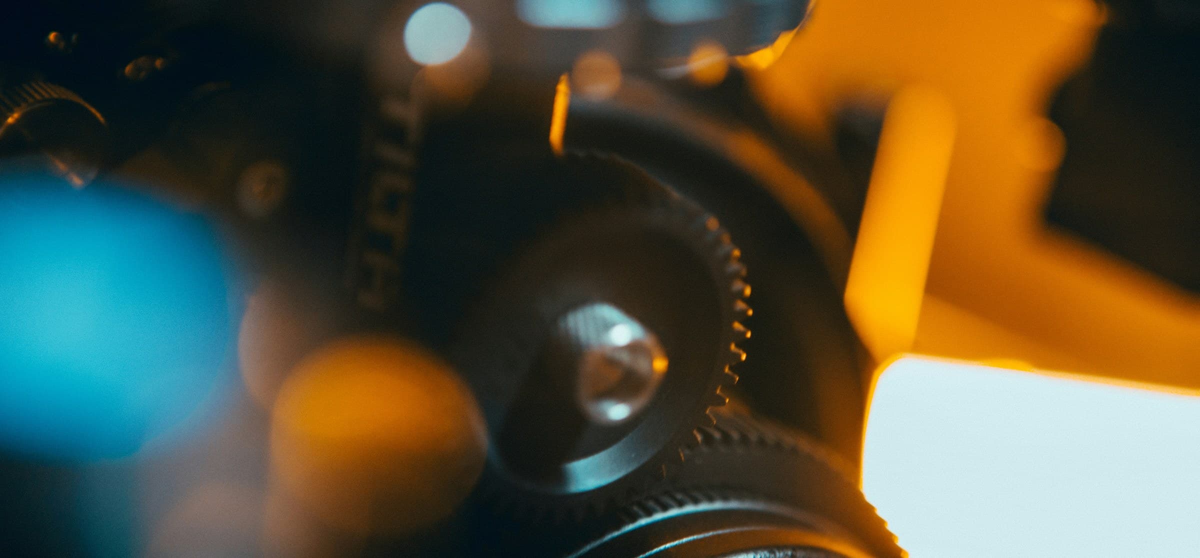 Macro detail of cinema camera follow-focus gear under warm and cool studio lighting
